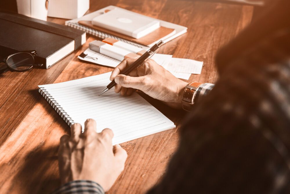 Asian young business man of student holding a pen writing letter on paper at home