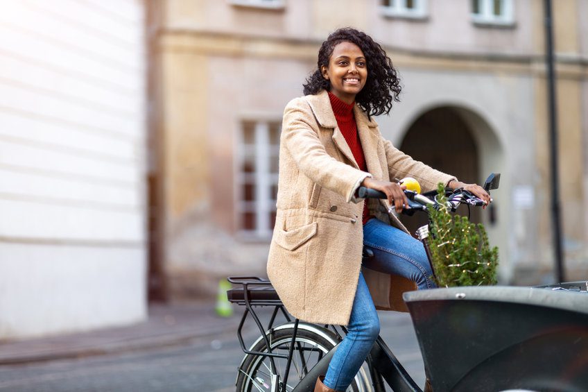 Young woman with small Christmas tree in a cargo bike